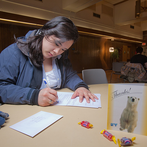 Student sits at a table completing paperwork 