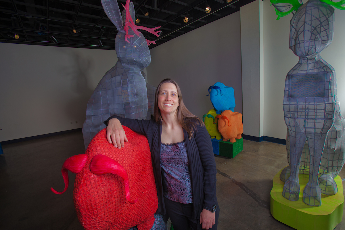 CLA Graduate Degrees Lacie Stiewing poses with a few of her creations during her master of fine arts exhibition, "Fabulaskana," in the UAF art gallery. | UAF Photo by Todd Paris