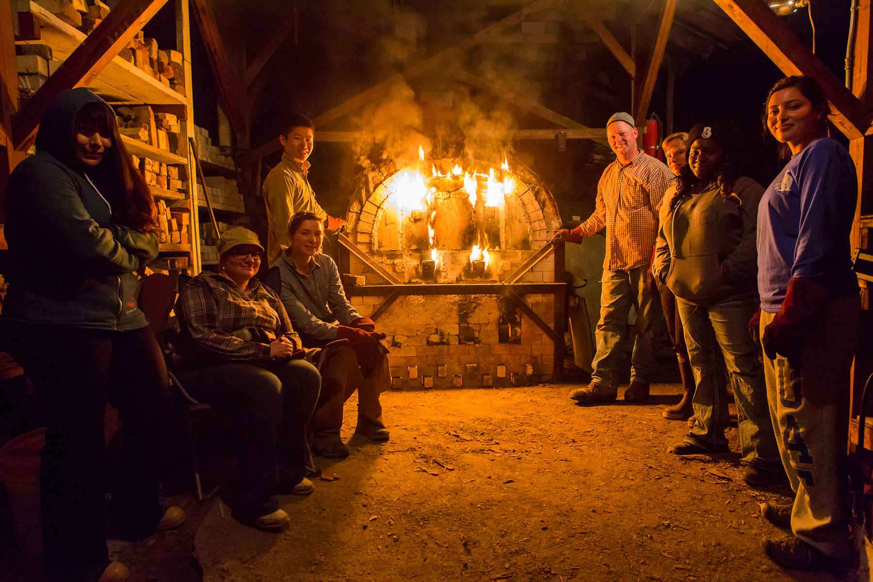UAF ceramics students and professor Jim Brashear pose for a portrait in front of the anagama, wood-fired kiln during a firing at the experimental farm early in the morning. | UAF Photo by JR Ancheta
