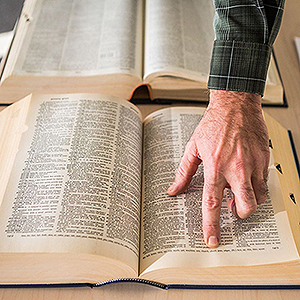 Several open books with a hand on one book