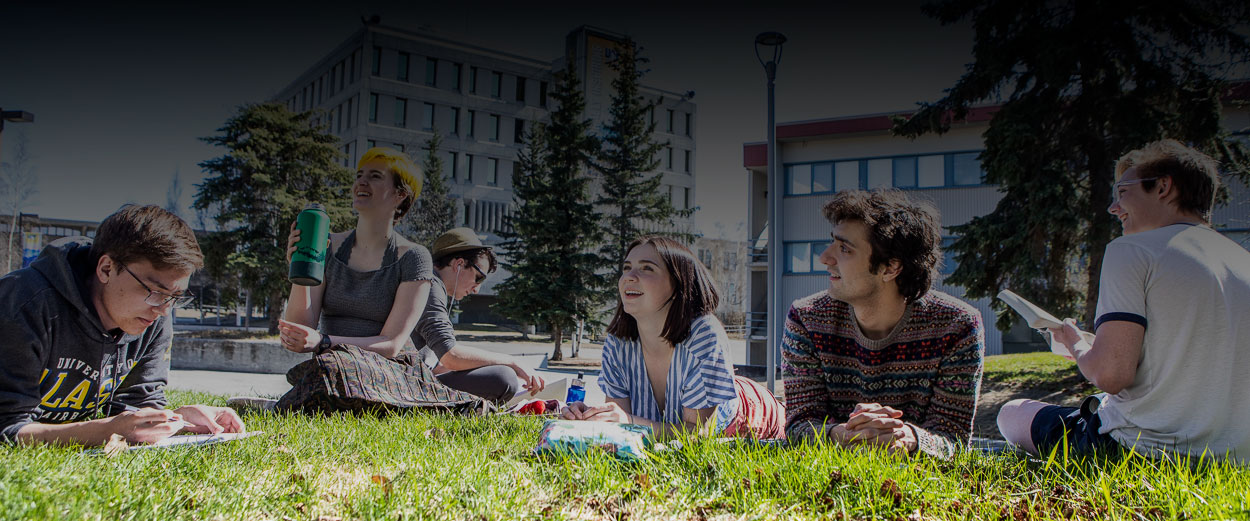 image of students hanging out in a field of grass